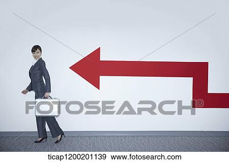 a businesswoman with walking pose next to an arrow on the wall View Large Photo Image Stock Photo - a businesswoman with walking pose next to an arrow on the wall. Fotosearch