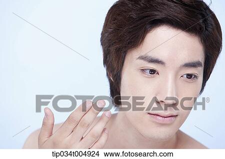 Picture - a close up shot of a topless man about to put on lotion. Fotosearch