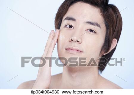 Stock Image - a close up shot of a topless man putting on lotion. Fotosearch