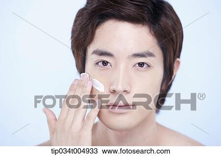 Stock Image - a close up shot of a topless man putting on white cream lotion. Fotosearch