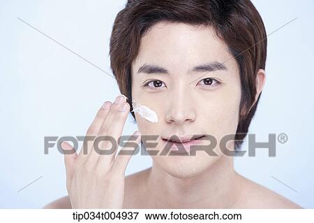 Stock Photo - a close up shot of a topless man putting on white cream lotion. Fotosearch