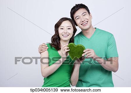 a couple in green t-shirts holding a heart shape figure made from grass View Large Photo Image Stock Photo - a couple in green t-shirts holding a heart shape figure made from grass. Fotosearch