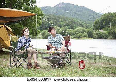 a couple sitting on camping chairs with camping grill in front View Large Photo Image Stock Photo - a couple sitting on camping chairs with camping grill in front . Fotosearch
