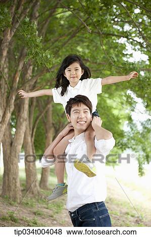 Stock Photo - a daughter on father's shoulders posing . Fotosearch