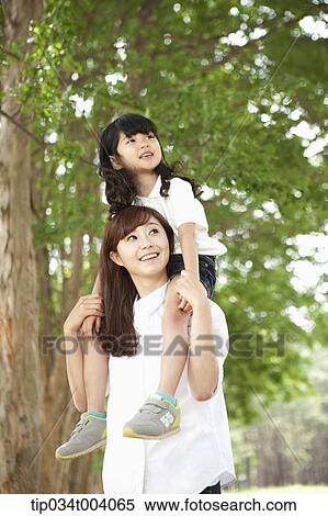 Stock Photography - a daughter on mother's shoulders in forest . Fotosearch