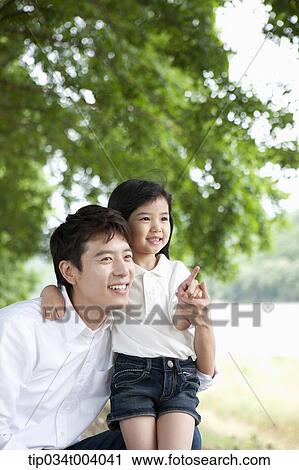 a daughter pointing somewhere while having a rest next to a field with a father View Large Photo Image Stock Image - a daughter pointing somewhere while having a rest next to a field with a father. Fotosearch