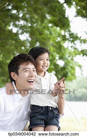 a daughter pointing somewhere while having a rest next to a field with a father View Large Photo Image Stock Image - a daughter pointing somewhere while having a rest next to a field with a father. Fotosearch