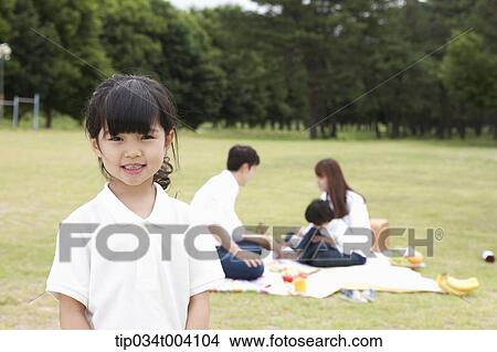 a daughter smiling with a background of family enjoying a picnic View Large Photo Image Picture - a daughter smiling with a background of family enjoying a picnic . Fotosearch