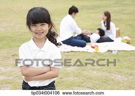 a daughter smiling with a background of family enjoying a picnic View Large Photo Image Stock Photograph - a daughter smiling with a background of family enjoying a picnic . Fotosearch
