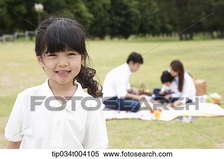 a daughter smiling with a background of family enjoying a picnic View Large Photo Image Stock Photography - a daughter smiling with a background of family enjoying a picnic . Fotosearch