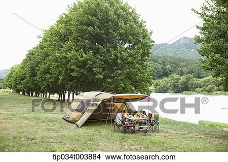 a family having a camping meal in camping place with trees and a lake View Large Photo Image Picture - a family having a camping meal in camping place with trees and a lake. Fotosearch