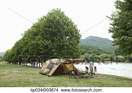Picture - a family in camping place cooking a meal. Fotosearch