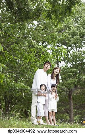 a family posing on grass with trees behind them View Large Photo Image Stock Image - a family posing on grass with trees behind them . Fotosearch