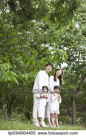 a family posing on grass with trees behind them View Large Photo Image Stock Image - a family posing on grass with trees behind them . Fotosearch