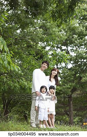 Stock Photography - a family posing on grass with trees behind them . Fotosearch