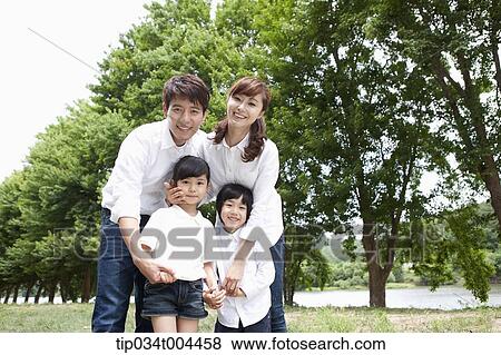 Stock Photo - a family posing with trees behind . Fotosearch