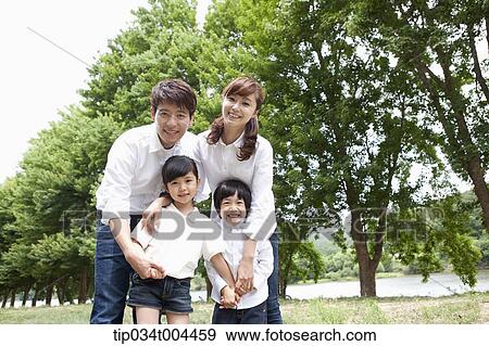 Stock Photo - a family posing with trees behind . Fotosearch