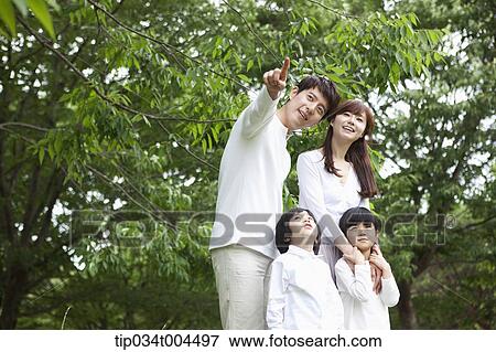 Stock Photo - a family posing with trees behind them . Fotosearch