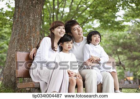 a family sitting on a bench smiling View Large Photo Image Stock Photo - a family sitting on a bench smiling . Fotosearch