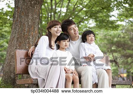 Stock Photo - a family sitting on a bench smiling . Fotosearch