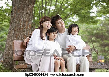 Stock Photograph - a family sitting on a bench smiling . Fotosearch