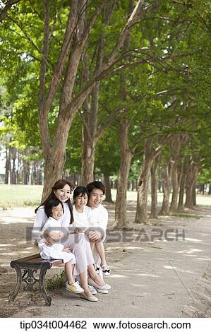 Stock Image - a family sitting on a bench . Fotosearch