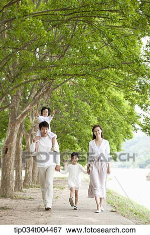 Stock Photo - a family walking along a trail with trees. Fotosearch