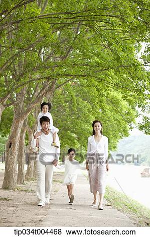 Stock Photo - a family walking along a trail with trees. Fotosearch