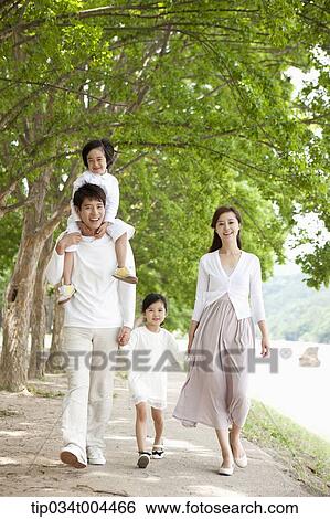 Stock Photograph - a family walking along a trail with trees. Fotosearch