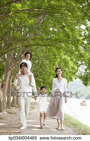 Stock Photography - a family walking along a trail with trees. Fotosearch