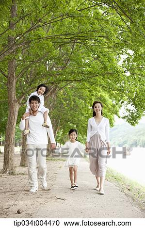 Stock Image - a family with kids walking along a trail with trees. Fotosearch
