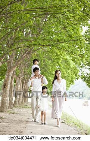 Stock Image - a family with kids walking along a trail with trees. Fotosearch