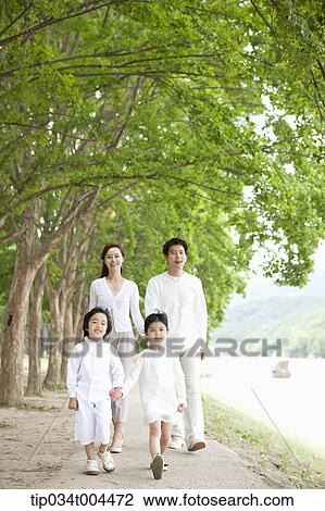 Stock Image - a family with kids walking along a trail with trees. Fotosearch