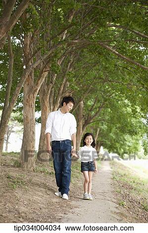 Picture - a father and a daughter taking a walk along trees . Fotosearch