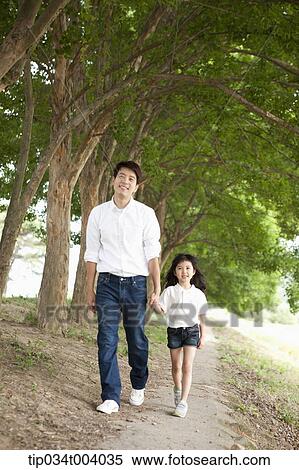 Stock Photography - a father and a daughter taking a walk along trees . Fotosearch