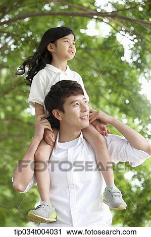 a father holding daughter on his shoulders in a forest View Large Photo Image Stock Image - a father holding daughter on his shoulders in a forest . Fotosearch