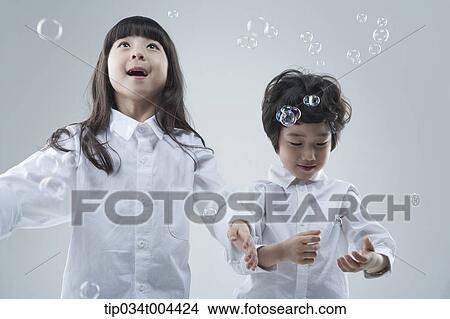 a female and a male kids trying to catch bubbles View Large Photo Image Picture - a female and a male kids trying to catch bubbles. Fotosearch
