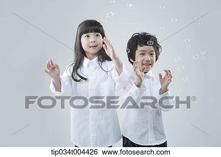 a female and a male kids trying to catch bubbles View Large Photo Image Stock Photograph - a female and a male kids trying to catch bubbles. Fotosearch