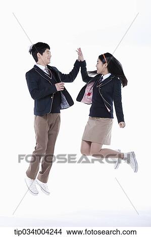 a female and a male student with school uniform doing high five while jumping View Large Photo Image Picture - a female and a male student with school uniform doing high five while jumping. Fotosearch