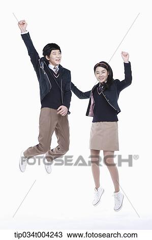Stock Image - a female and a male student with school uniform jumping . Fotosearch