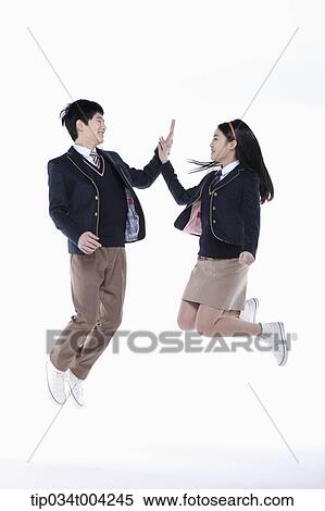 a female and a male student with school uniform doing high five while jumping View Large Photo Image Stock Photography - a female and a male student with school uniform doing high five while jumping. Fotosearch