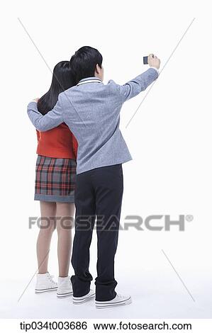 a female and male student's back of them taking a photo with a mobile phone View Large Photo Image Stock Photograph - a female and male student's back of them taking a photo with a mobile phone . Fotosearch