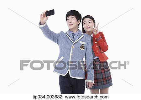 Stock Image - a female and male students taking a photo with a mobile phone. Fotosearch
