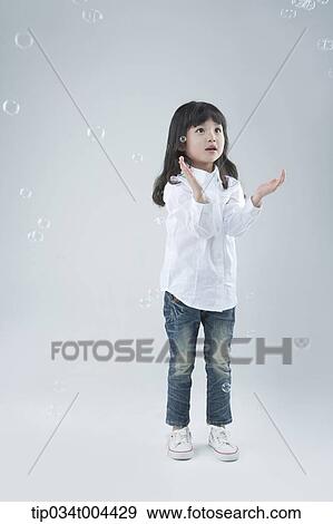 Stock Photo - a female kid playing with bubbles. Fotosearch