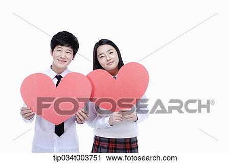 Stock Image - a female student and male student holding pink cushions. Fotosearch