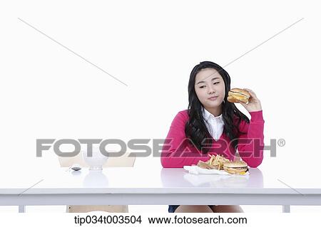 Picture - a female student holding a burger. Fotosearch