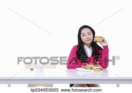 Stock Image - a female student holding a burger. Fotosearch