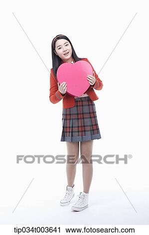 Stock Image - a female student holding a pink heart cushion. Fotosearch
