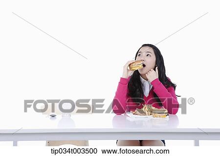 Stock Image - a female student in red sweater having a burger. Fotosearch