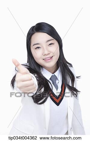 Stock Image - a female student in school uniform wearing a white jacket showing thumbs up towards camera. Fotosearch